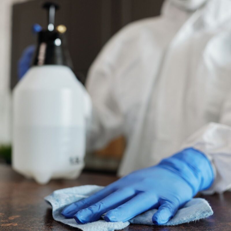 Gloved hand sanitizing a surface with disinfectant during biohazard cleaning