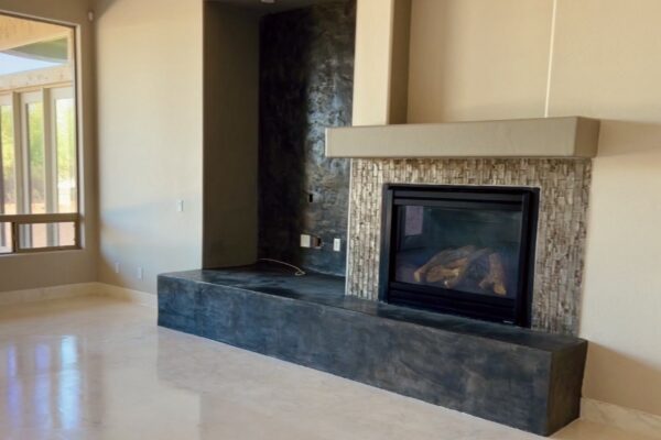 Remodeled gas fireplace with stacked stone surround, floating mantel and dark plaster hearth by Western Construction & Restoration