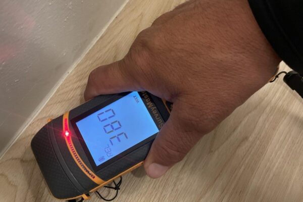 Technician checking flooring with a moisture meter during a water damage inspection by Western Construction & Restoration