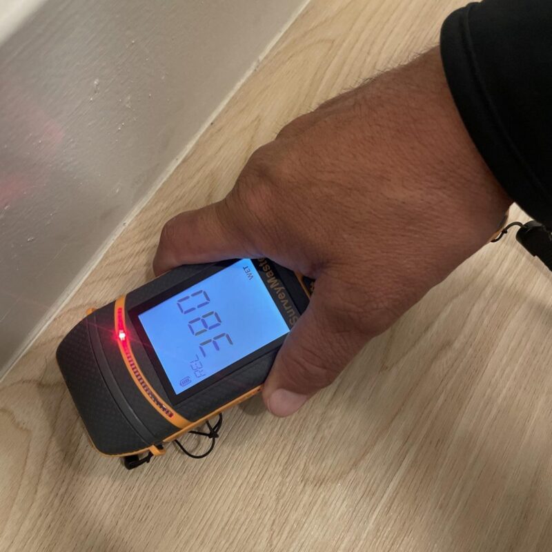 Technician checking flooring with a moisture meter during a water damage inspection by Western Construction & Restoration